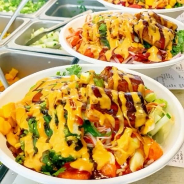 Two colorful poke bowls with various toppings and sauces, ready to be served.
