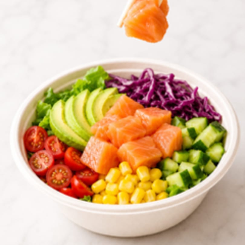 A colorful poke bowl with salmon, avocado, corn, tomatoes, cucumber, and red cabbage.