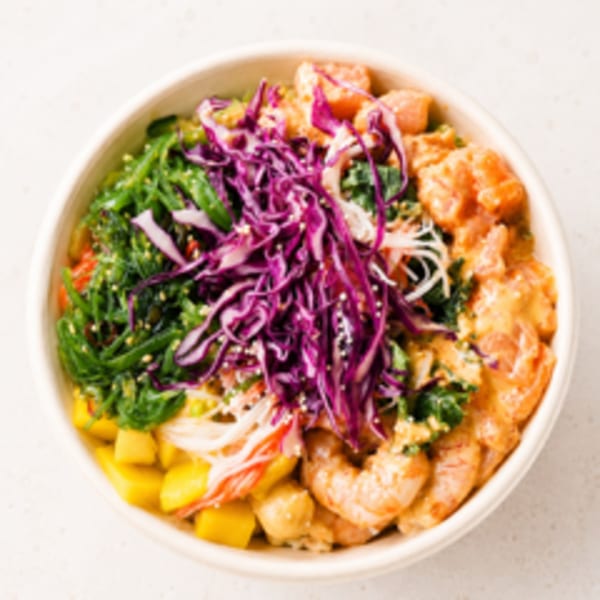 Colorful poke bowl with shrimp, salmon, mango, seaweed, and purple cabbage.