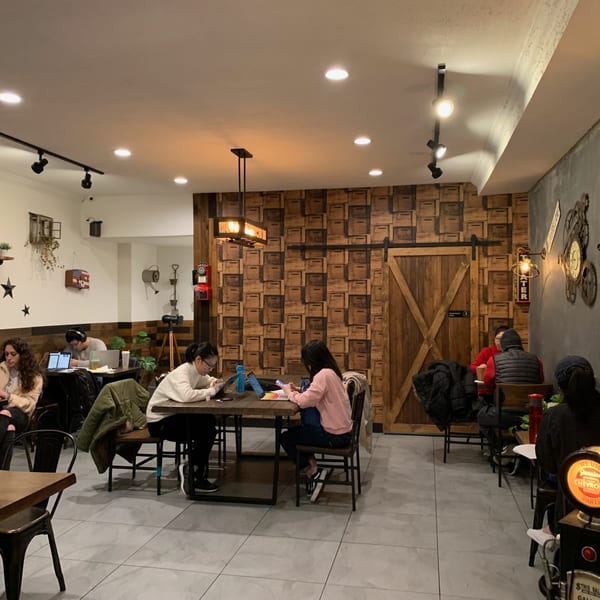 Customers work and relax at tables in a cafe with rustic decor and modern lighting.