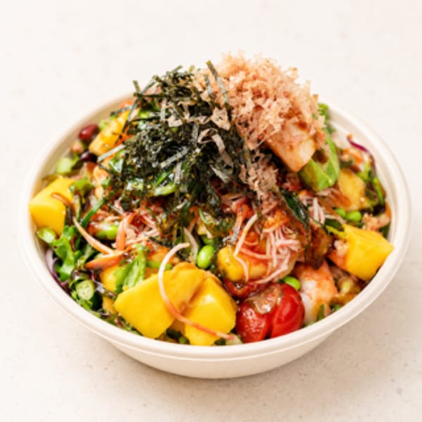 A colorful poke bowl with mango, edamame, tomatoes, seaweed, and bonito flakes.
