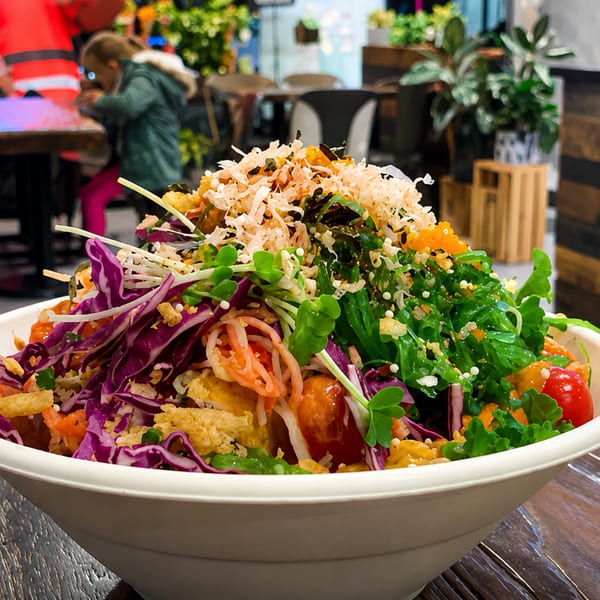 A vibrant poke bowl overflowing with fresh ingredients, including purple cabbage, greens, and crispy toppings.