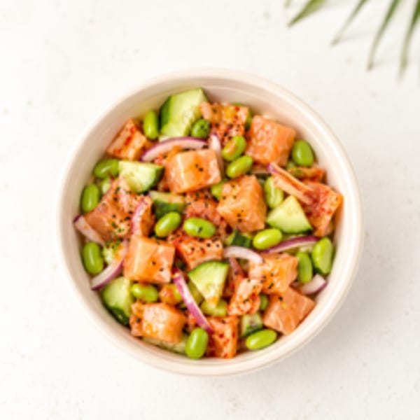Overhead view of a poke bowl with salmon, edamame, cucumber, and red onion.